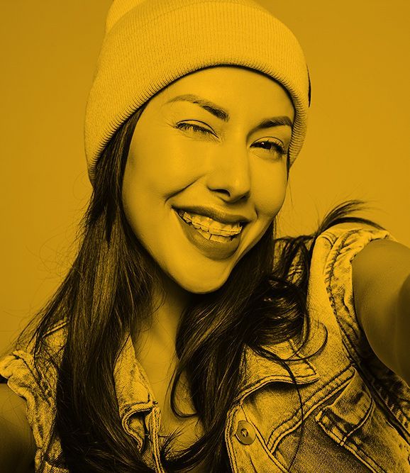 Portrait of beautiful cute brunette woman model in casual summer jeans clothes with no makeup in purple beanie making selfie photo on smartphone isolated on gray